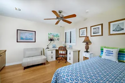 a bedroom with a bed and a desk and a ceiling fan at 152-4 Coastal Luxury with Panoramic Ocean View in Oceanside