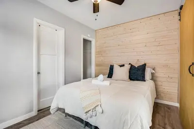 a bedroom with a large bed with a wooden wall at 1BD Remodeled Craftsman Cottage Free parking Heart of lIttle Italy in San Diego