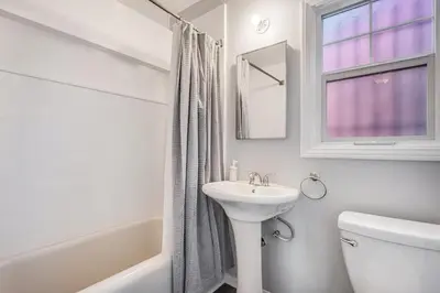 a white bathroom with a sink and a toilet and a window at 1BD Remodeled Craftsman Cottage Free parking Heart of lIttle Italy in San Diego
