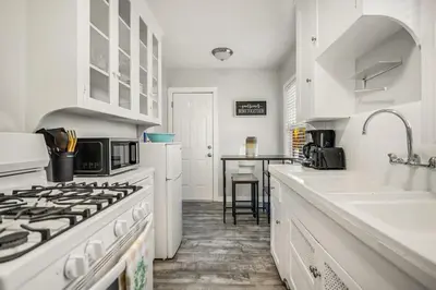 a white kitchen with a stove and a sink at 1BD Remodeled Craftsman Cottage Free parking Heart of lIttle Italy in San Diego