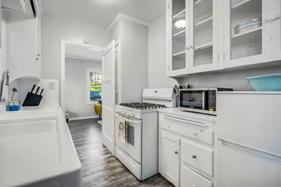 a white kitchen with a stove and a microwave at 1BD Remodeled Craftsman Cottage Free parking Heart of lIttle Italy in San Diego