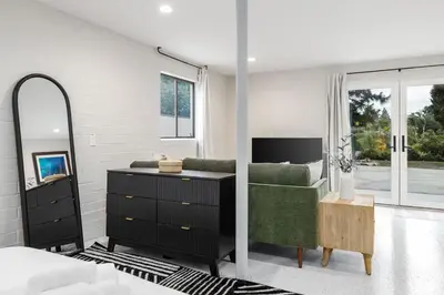 a bedroom with a green couch and a mirror at Brand New Studio in Carlsbad in Carlsbad