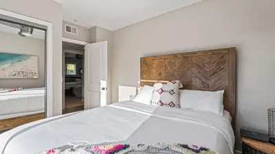 a bedroom with a large white bed with a wooden headboard at Steps to the Beach Hot Tub Fire Pit 257 Trailhead Trestles 2 by AvantStay in San Clemente