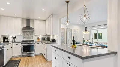 a kitchen with white cabinets and a large island at Steps to the Beach Hot Tub Fire Pit 257 Trailhead Trestles 2 by AvantStay in San Clemente