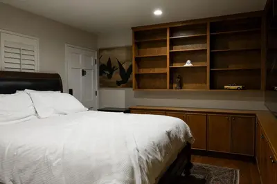 a bedroom with a white bed and wooden shelves at Bridgeview Retreat Near Balboa Park in San Diego