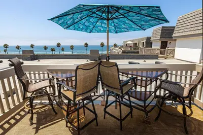a table and chairs with an umbrella on a balcony at North Coast Village Penthouse A306 in Oceanside