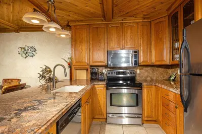 a kitchen with wooden cabinets and stainless steel appliances at North Coast Village Penthouse A306 in Oceanside