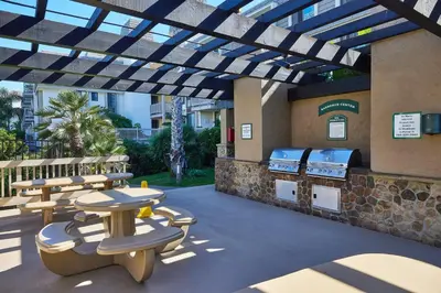 a patio with a grill and tables and benches at North Coast Village B212 in Oceanside