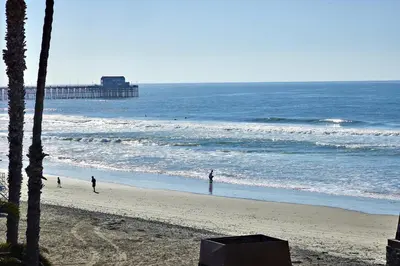 a beach with a pier and people in the ocean at North Coast Village D204 in Oceanside