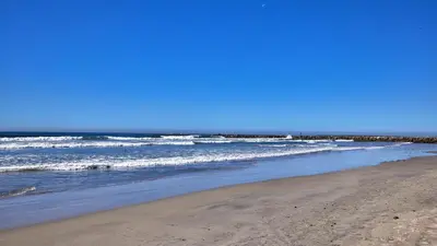 a sandy beach with waves in the ocean at North Coast Village Cottage G20 in Oceanside