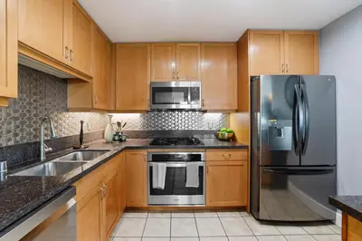 a kitchen with wooden cabinets and a stainless steel refrigerator at 3BR Downtown Peaceful Corner in San Diego