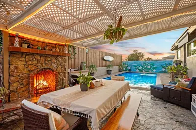 a patio with a table and a fireplace and a pool at Casa Malta Spa and Pool in San Diego