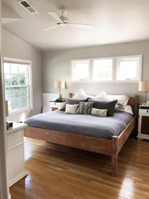 a bedroom with a large wooden bed with two windows at La Jolla Beach Cottage in San Diego