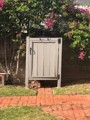 a door on a brick yard with pink flowers at La Jolla Beach Cottage in San Diego