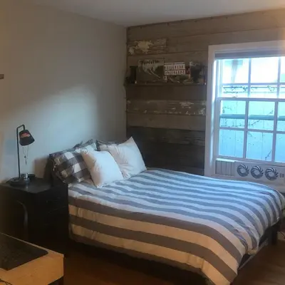 a bedroom with a bed with a blue blanket and a window at La Jolla Beach Cottage in San Diego
