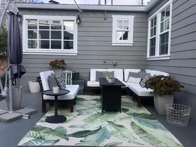 a patio with white couches and tables on a house at La Jolla Beach Cottage in San Diego
