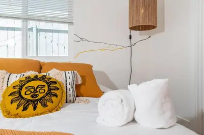 a bed with white sheets and pillows on it at Artist micro-villa with kitchen, firepit & theater in San Diego