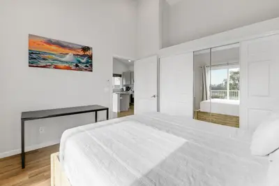 a white bedroom with a large bed and a kitchen at Bright Spacious Modern Getaway in San Diego