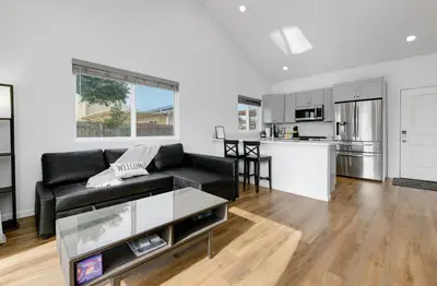 a living room with a black couch and a kitchen at Bright Spacious Modern Getaway in San Diego