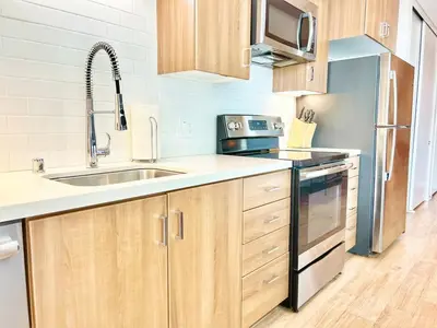 a kitchen with wooden cabinets and a sink at Urban Oasis w Rooftop Views Heart of San Diego in San Diego