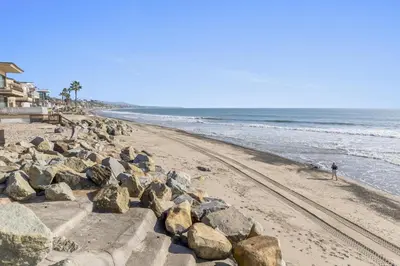 a beach with rocks and a person walking on the beach at Hawaiian Style Beachfront on Beach Road in Dana Point
