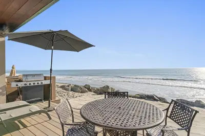 a table and chairs with an umbrella on the beach at Hawaiian Style Beachfront on Beach Road in Dana Point