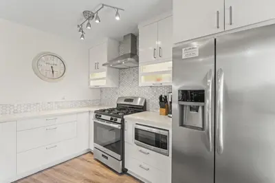 a kitchen with white cabinets and a stainless steel refrigerator at Hideaway D Walk to the beach Downtown AC in San Clemente