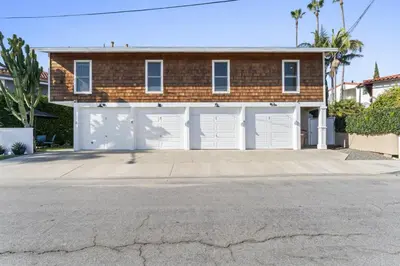 a brick house with white garage doors on a street at Hideaway D Walk to the beach Downtown AC in San Clemente