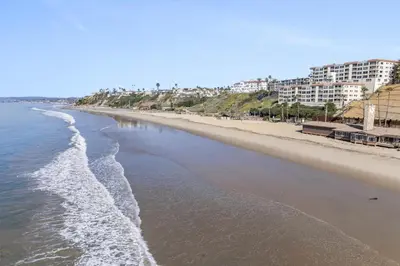 an empty beach with buildings in the background at Hideaway D Walk to the beach Downtown AC in San Clemente