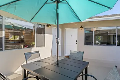a table with a blue umbrella on a patio at Hideaway D Walk to the beach Downtown AC in San Clemente