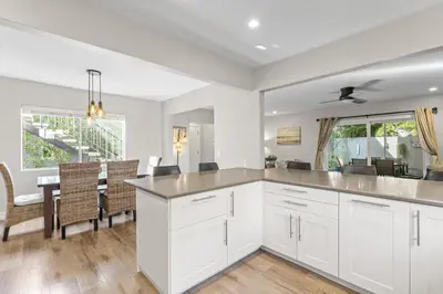 a kitchen with white cabinets and a dining room with a table at Hideaway A Walk to the beach Downtown AC in San Clemente