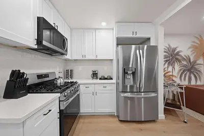 a kitchen with white cabinets and a stainless steel refrigerator at Modern 2BR in Prime Location with Board Games in San Diego