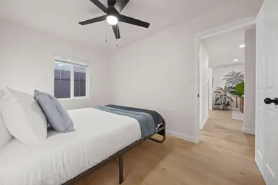 a white bedroom with a bed with a ceiling fan at Modern 2BR in Prime Location with Board Games in San Diego