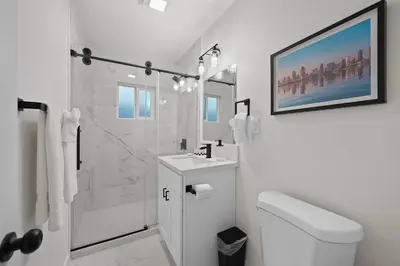 a white bathroom with a toilet and a shower at Modern 2BR in Prime Location with Board Games in San Diego