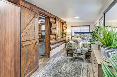 a living room with wooden walls and a sliding barn door at MTB Base Camp! Rustic Cabin By Mt Laguna Trails in Mount Laguna