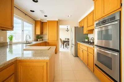 a kitchen with wooden cabinets and stainless steel appliances at Peaceful Poolside Perfection near Wine Country in Murrieta