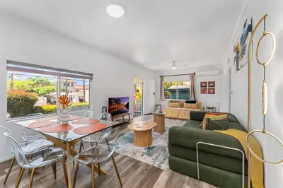 a living room with a table and a green couch at 3BR Home w/Big Yard, Close to Shops & Attractions in San Diego