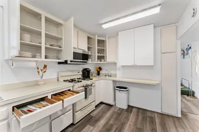 a white kitchen with white cabinets and a refrigerator at 3BR Home w/Big Yard, Close to Shops & Attractions in San Diego