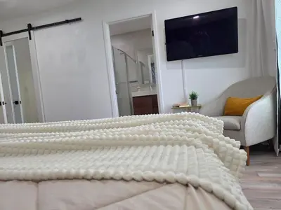 a bedroom with a white bed with a television on the wall at Sunny 5BEDR00MS with Pool, Zip Line, Game Room, Kid's Playhouse in San Diego