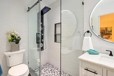 a bathroom with a shower with a toilet and a sink at Newport Beach Lux in Newport Beach
