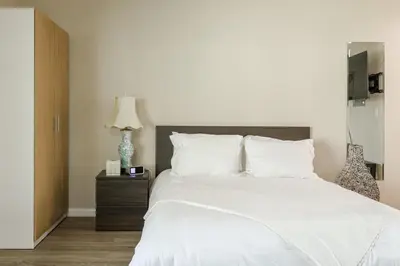 a bedroom with a large white bed and a lamp at Cozy Studio Near Balboa Park in San Diego