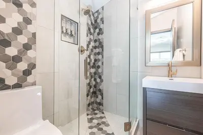 a bathroom with a shower and a toilet and a sink at 8Br Retreat With Ac, Modern Upgrades, And Two Rooftop Decks By Beachview Rentals in Newport Beach