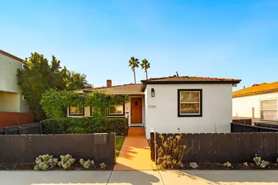 a white house with a fence in front of it at Little Italy Delight 3 bedroom backyard parking in San Diego