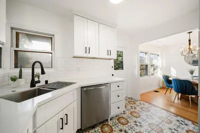 a kitchen with white cabinets and a sink and a table at Little Italy Home with Parking and Backyard in San Diego