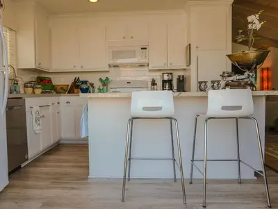a kitchen with white cabinets and two bar stools at 2 Bdr 2 bath luxury home steps away from Mission Beach 5 min from Belmont in San Diego