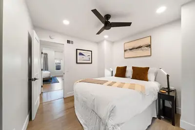 a white bedroom with a bed and a ceiling fan at Cozy Coastal Townhome in the Heart of Pacific Beach in San Diego