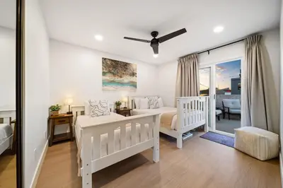a bedroom with two beds and a living room at Cozy Coastal Townhome in the Heart of Pacific Beach in San Diego