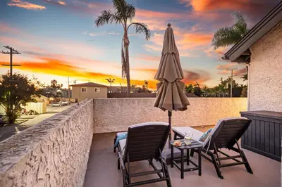 a patio with two chairs and an umbrella and a table at Cozy Coastal Townhome in the Heart of Pacific Beach in San Diego