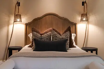 a bed with a wooden head board and two lights at ResortHome Pickle Ball Pool MovieRoom Gym Sauna Villa in Del Mar