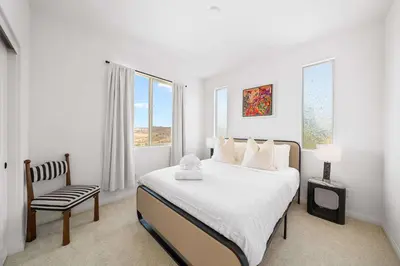 a white bedroom with a bed and a chair at Marbella Lane - Curated 5BR in Upscale RMV Haven in Ladera Ranch